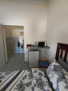 a bedroom with a bed and a kitchen with a microwave at The Lantern Porch Guesthouse in Vryburg