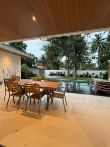 a wooden table and chairs on a patio with a pool at Villa Manu in Ko Phangan