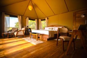 a bedroom with a bed and a table and chairs at Bushland Luxury Camp in Serengeti