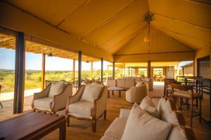 a large room with chairs and tables and windows at Bushland Luxury Camp in Serengeti +7 photos