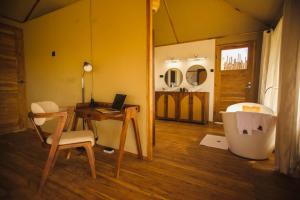 a room with a desk and a table and a tub at Bushland Luxury Camp in Serengeti