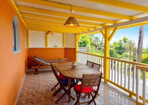a porch with a wooden table and chairs on a balcony at Maison charmante à Le Diamant avec vue sur mer et jardin in Le Diamant
