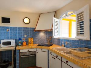 a kitchen with a sink and a microwave at Maison charmante à Le Diamant avec vue sur mer et jardin in Le Diamant +21 photos