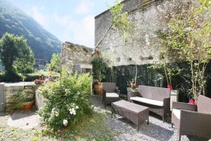 a patio with chairs and a couch in front of a building at Le chant de la garonne in Saint-Béat