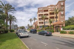 a street with cars parked in front of a building at Inmacanela playa in Isla Canela