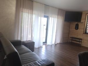a living room with a couch and large windows at Foresthillсоttage in Tyshovnitsa