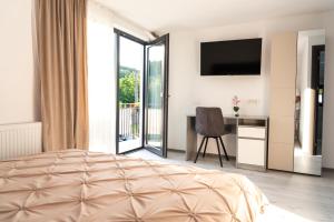 a bedroom with a bed and a desk with a television at Casa Andrei Guesthouse in Bărăşti