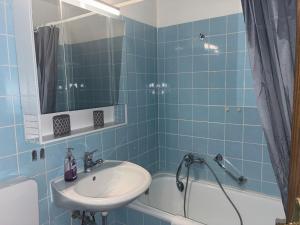 a blue tiled bathroom with a sink and a tub at Apartment 231 in Hohegeiß