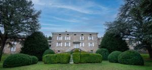 a large brick building with bushes in front of it at Manoir majestueux à Satillieu avec piscine privée in Satillieu +50 photos