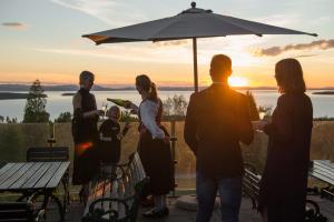 a group of people standing on a patio with an umbrella at Green Hotel in Tällberg