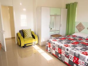 a bedroom with a bed and a yellow chair at Cozy studio in Trou-aux-Biches 35 m² with lovely garden balcony in Trou aux Biches