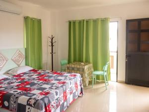 a bedroom with a bed and green curtains and a table at Cozy studio in Trou-aux-Biches 35 m² with lovely garden balcony in Trou aux Biches