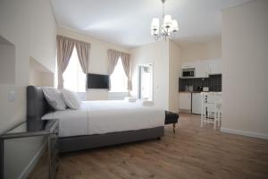 a bedroom with a large white bed and a kitchen at Suites Guest House in Cascais