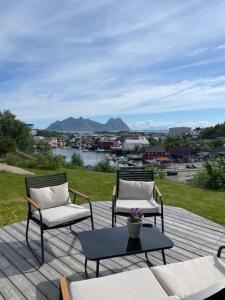 two chairs and a coffee table on a deck with a view at Sentrumsnær sokkelleilighet in Svolvær
