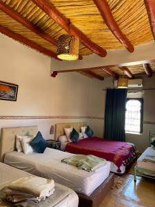 a bedroom with two beds and a wooden ceiling at dar boumida in Lalla Takerkoust +53 photos