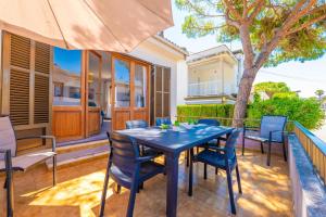 a blue table and chairs on a patio with a tree at PDM CA'N NOFRE in Playa de Muro