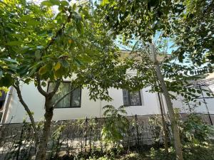 a white house with trees in front of it at Просторный дом с садом in Qŭyliq