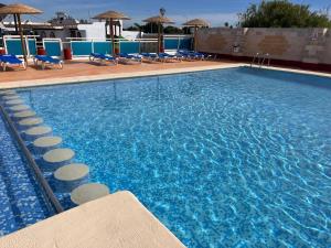a large swimming pool with blue chairs and umbrellas at Camping La Aventura Playa in Daimuz