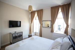 una camera con due letti, una TV e finestre di Suites Guest House a Cascais