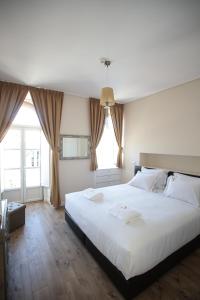 a bedroom with a large white bed and two windows at Suites Guest House in Cascais