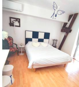 a bedroom with a white bed and a chair at Morphoses, Maison de créatrice & parc privé près de Chenonceaux in Chissay-en-Touraine