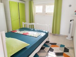 a bedroom with a bed with green curtains and a rug at Appartement charmant à Sainte-Rose avec terrasse et jardin in Sainte-Rose