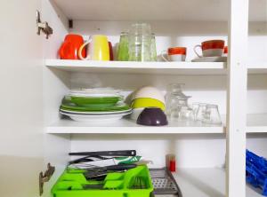 a kitchen shelf with dishes and utensils at Appartement charmant à Sainte-Rose avec terrasse et jardin in Sainte-Rose