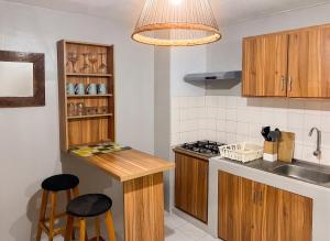 a kitchen with wooden cabinets and a counter with stools at Charming Studio in Grand Baie, 60 m² with Shared Pool in Grand-Baie