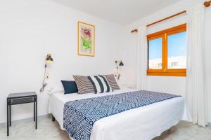 a white bedroom with a bed and a window at Can Fusteret in Son Serra de Marina