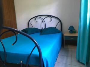 a bed with blue sheets and pillows in a room at Appartement cosy avec piscine privée, Le François, 40 m² in Le François