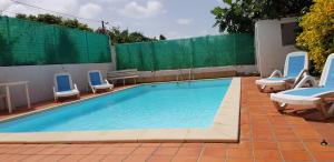 a swimming pool with blue chairs and a fence at Appartement cosy avec piscine privée, Le François, 40 m² in Le François +10 photos