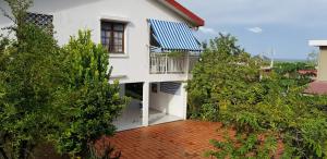 a white house with a blue roof and trees at Appartement cosy avec piscine privée, Le François, 40 m² in Le François
