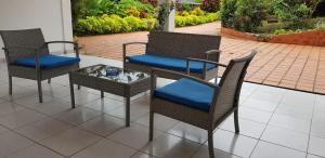 three wicker chairs and a table with a blue cushion at Appartement cosy avec piscine privée, Le François, 40 m² in Le François