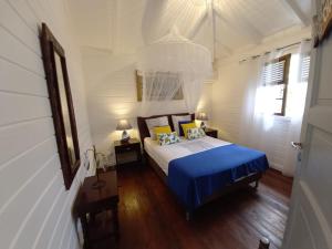 a bedroom with a bed with blue sheets and a window at Villa élégante à Bouillante avec piscine privée in Bouillante +55 photos