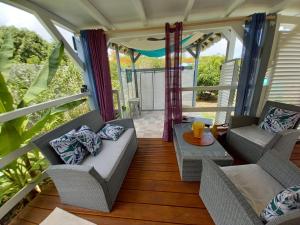 a porch with two chairs and a couch and a table at Villa élégante à Bouillante avec piscine privée in Bouillante