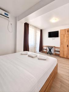 a bedroom with a large white bed with two towels at Harmony Rooms & Studios in Constanţa