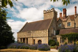 an old stone house with purple flowers in front of it at Nutfield Priory Hotel & Spa in Redhill