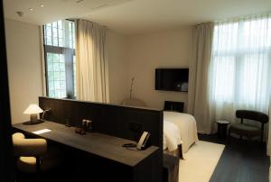 a hotel room with a bed and a desk with a phone at Priorij Corsendonk in Oud-Turnhout