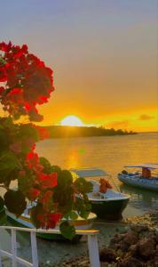 a sunset over the water with boats on the shore at Flatmoitas in Amontada