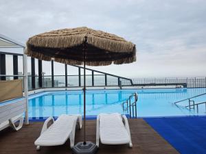 a pool with two chairs and an umbrella at Blue Terra Sokcho in Sokcho
