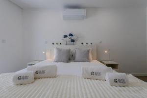 a white bedroom with a large bed with white sheets and pillows at GuestReady - Sea Apartments in São Roque