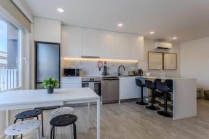 an open kitchen with white cabinets and black chairs at GuestReady - Sea Apartments in São Roque