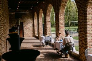 two people sitting at tables in a brick building at Priorij Corsendonk in Oud-Turnhout