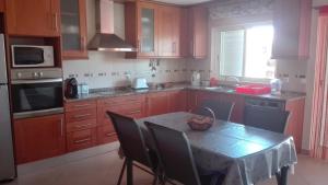 a kitchen with wooden cabinets and a table with chairs at Spacious house in Aldeia dos Pinheiros with pool in Azeitao