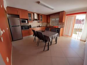 a kitchen with a table with chairs and a refrigerator at Spacious house in Aldeia dos Pinheiros with pool in Azeitao