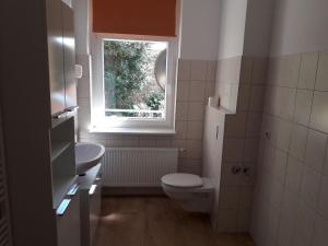 a bathroom with a toilet and a sink and a window at Specht-Ferienwohnung-1-Tangermuende in Tangermünde