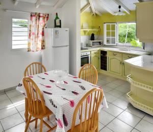 a kitchen with a table with chairs and a white refrigerator at Appartement convivial au Moule avec jardin clôturé in Le Moule