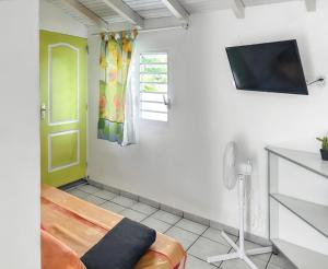 a room with a bed and a television on a wall at Appartement convivial au Moule avec jardin clôturé in Le Moule