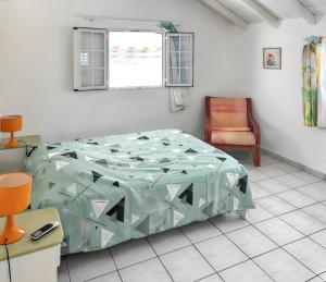 a bedroom with a bed and a chair and a window at Appartement convivial au Moule avec jardin clôturé in Le Moule