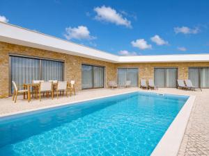 a pool with a table and chairs next to a building at Villa Flamingo - BY SCH in Nadadouro